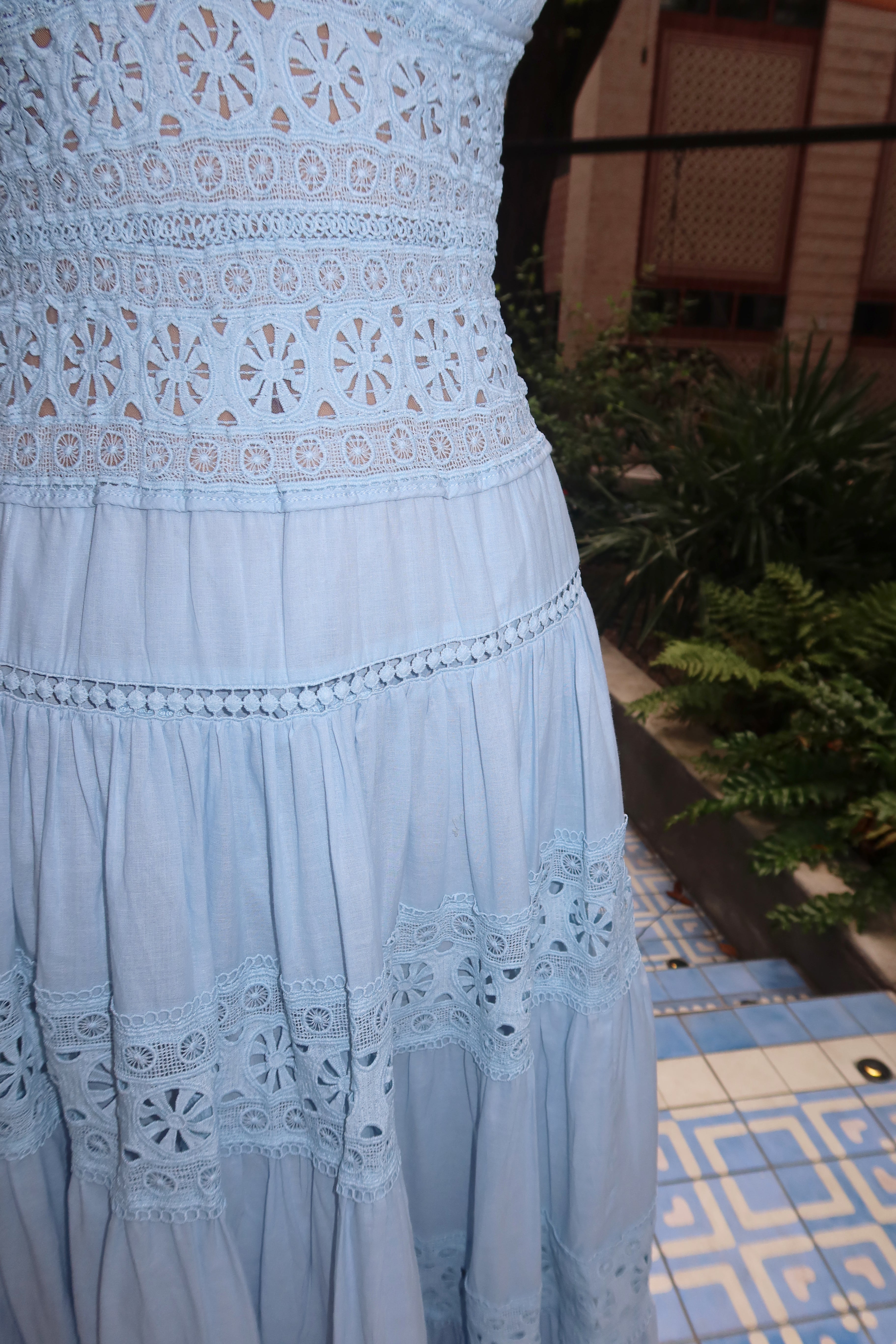 Light blue dress with intricate lace detailing on a patterned floor.