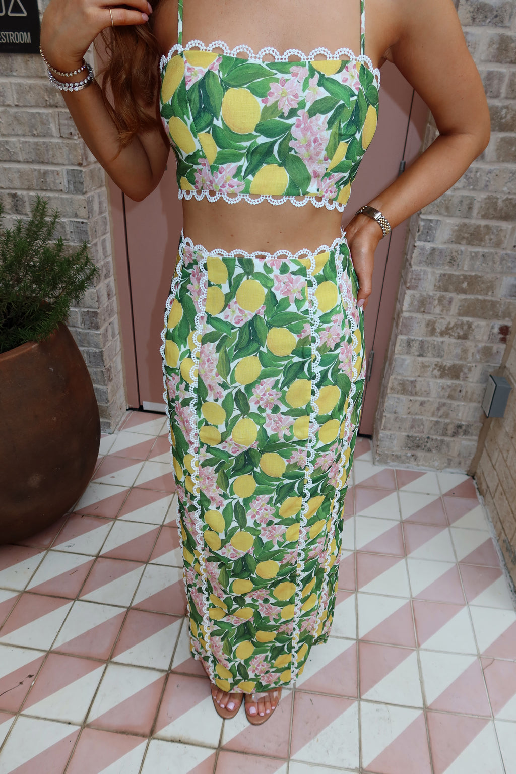 Woman wearing a floral dress with lemon pattern on a tiled floor.