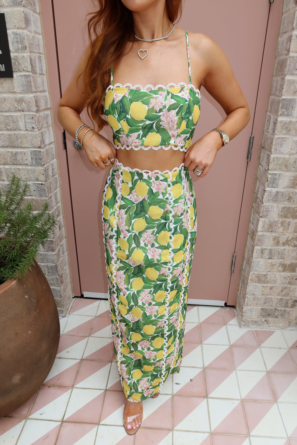 Woman wearing a floral dress with lemon pattern standing in front of a door.