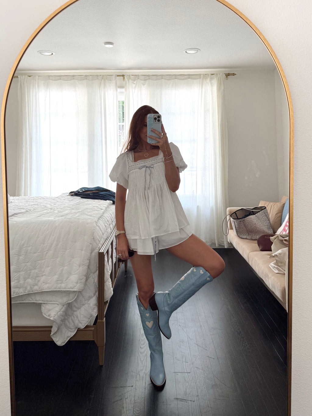 Person taking a mirror selfie wearing a white dress and blue rain boots in a bedroom.